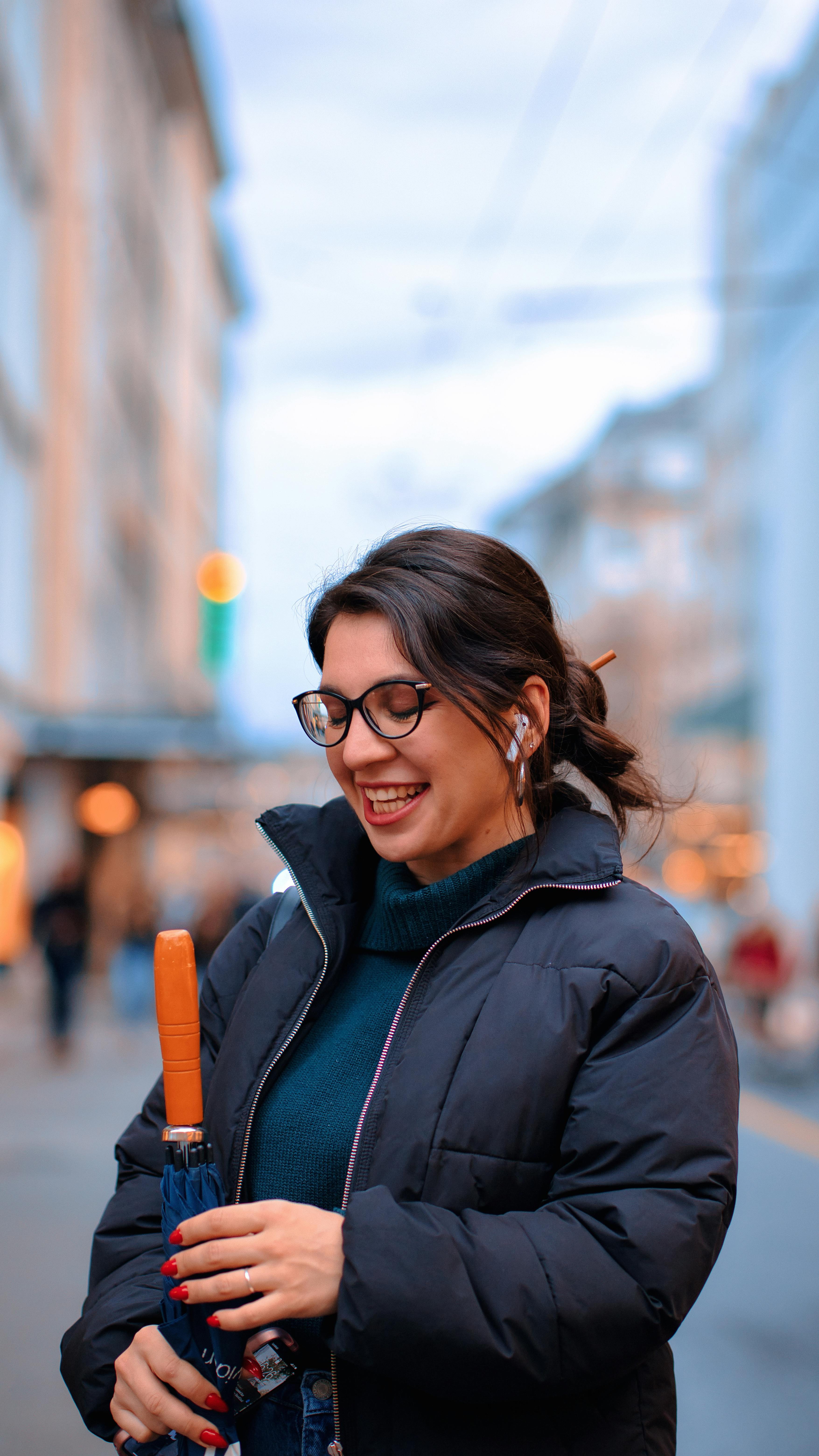 Junge Frau mit AirPods lächelt auf einer Stadtstraße