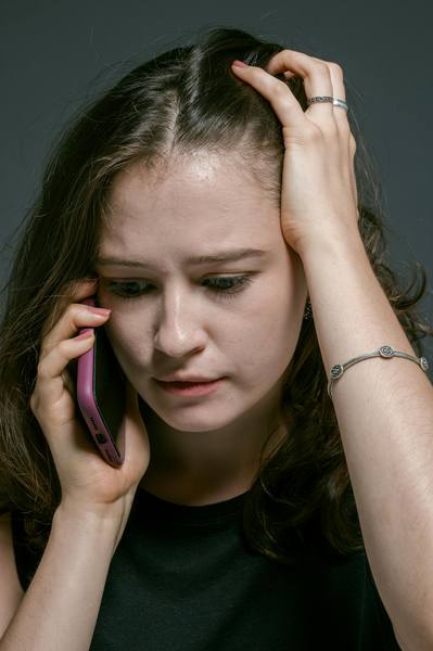 Frau mit angespanntem Gesichtsausdruck hält Smartphone ans Ohr